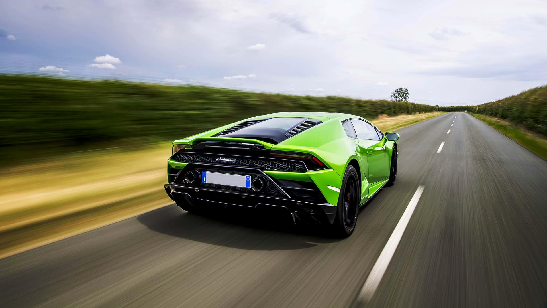 Vert vif Lamborghini Huracán Evo accélérant sur une route de campagne par une journée ensoleillée.