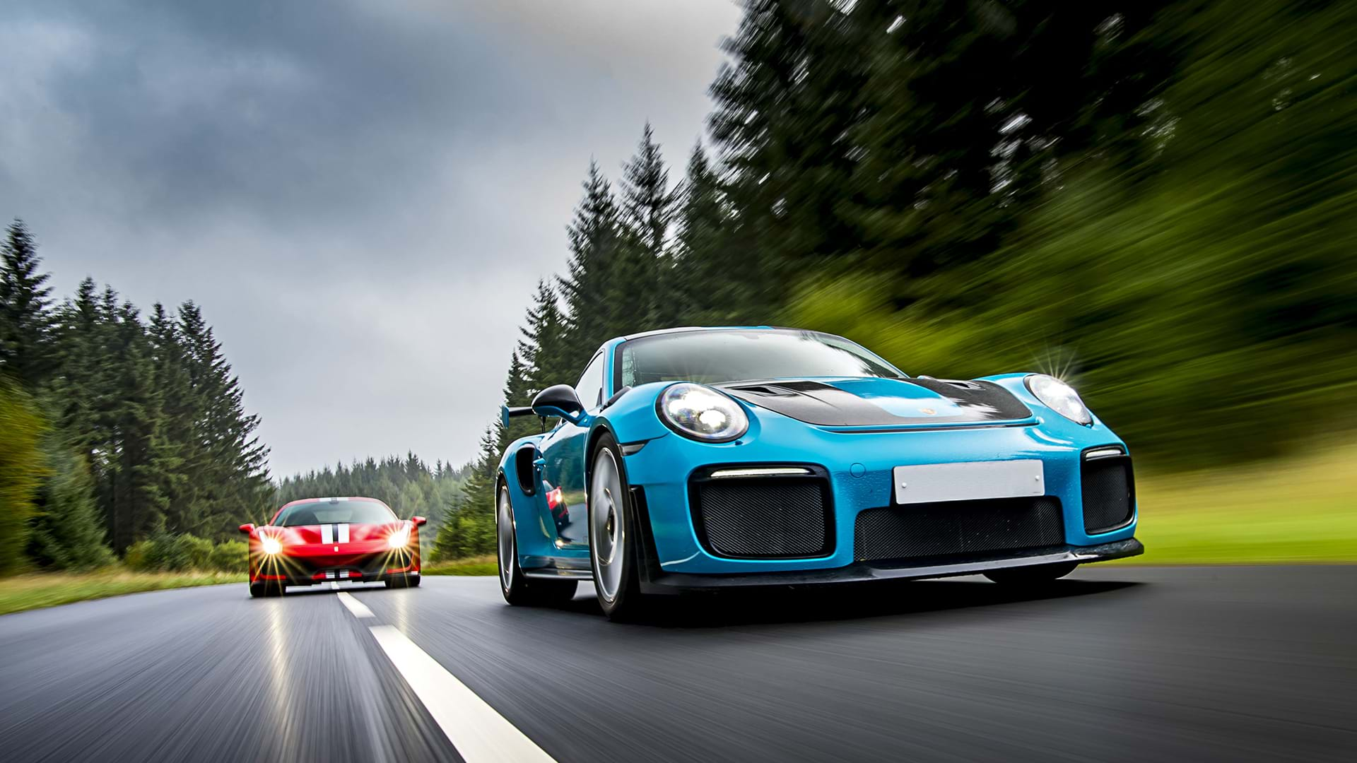 Bleu Porsche 991 GT3 RS menant une Pista rouge Ferrari 488 sur une route panoramique. 